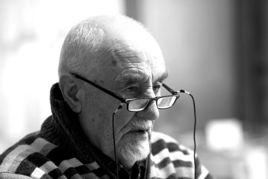 Black and white image of an elderly man sitting down and looking off to the right