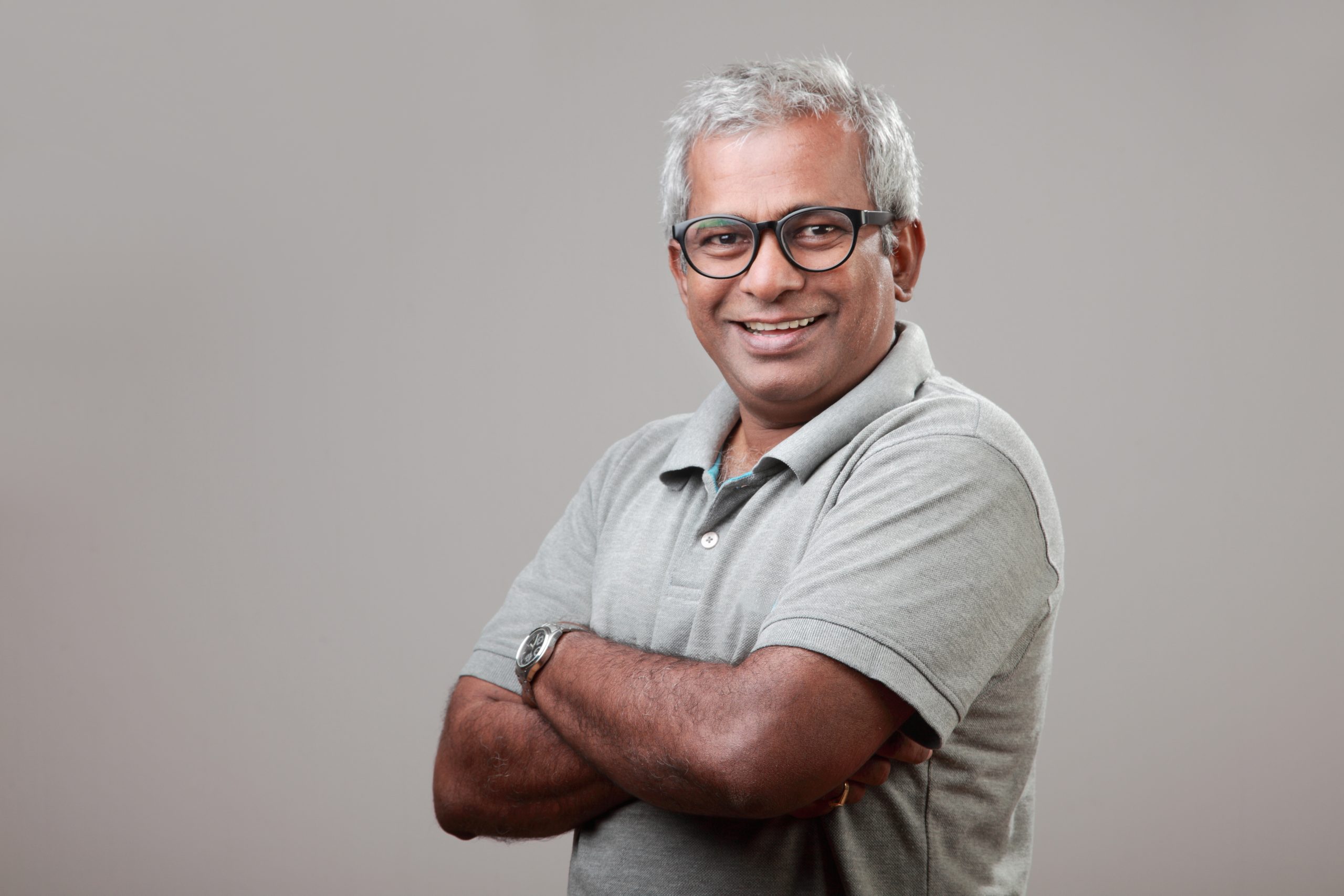 Middle Aged man wearing glasses smiling at the camera with his arms crossed