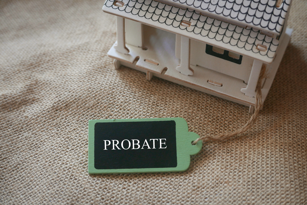 A Toy Wooden House On A Rugs With A Wooden tag labelled 'Probate'