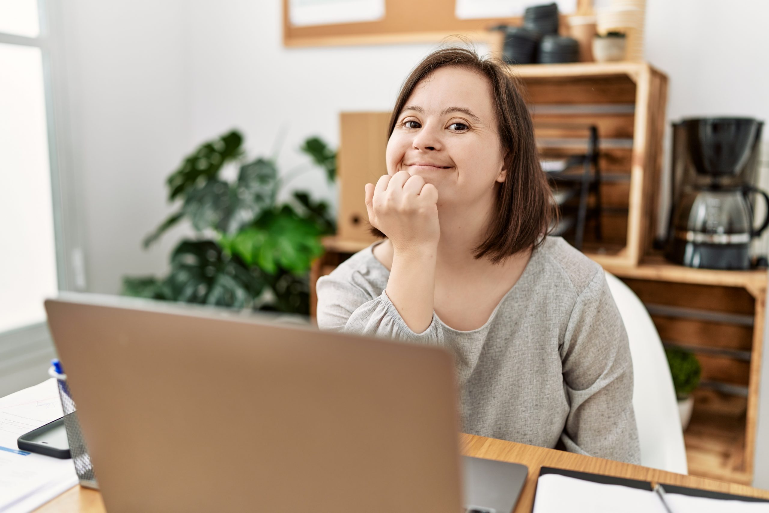 Woman smiling at the camera in front of her laptop