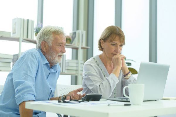 Older man looking at laptop with woman